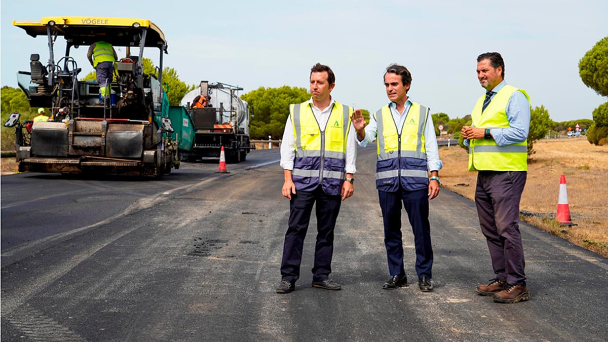 Trabajadores con equipamiento de seguridad realizando tareas de asfaltado en la carretera entre Matalascañas y Mazagón