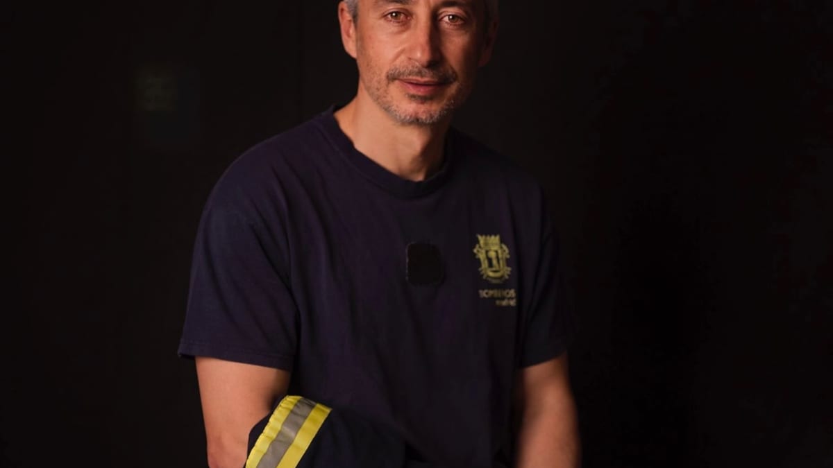 Bombero especialista posando para retrato profesional en estudio con uniforme azul y equipo de seguridad con reflectantes amarillos