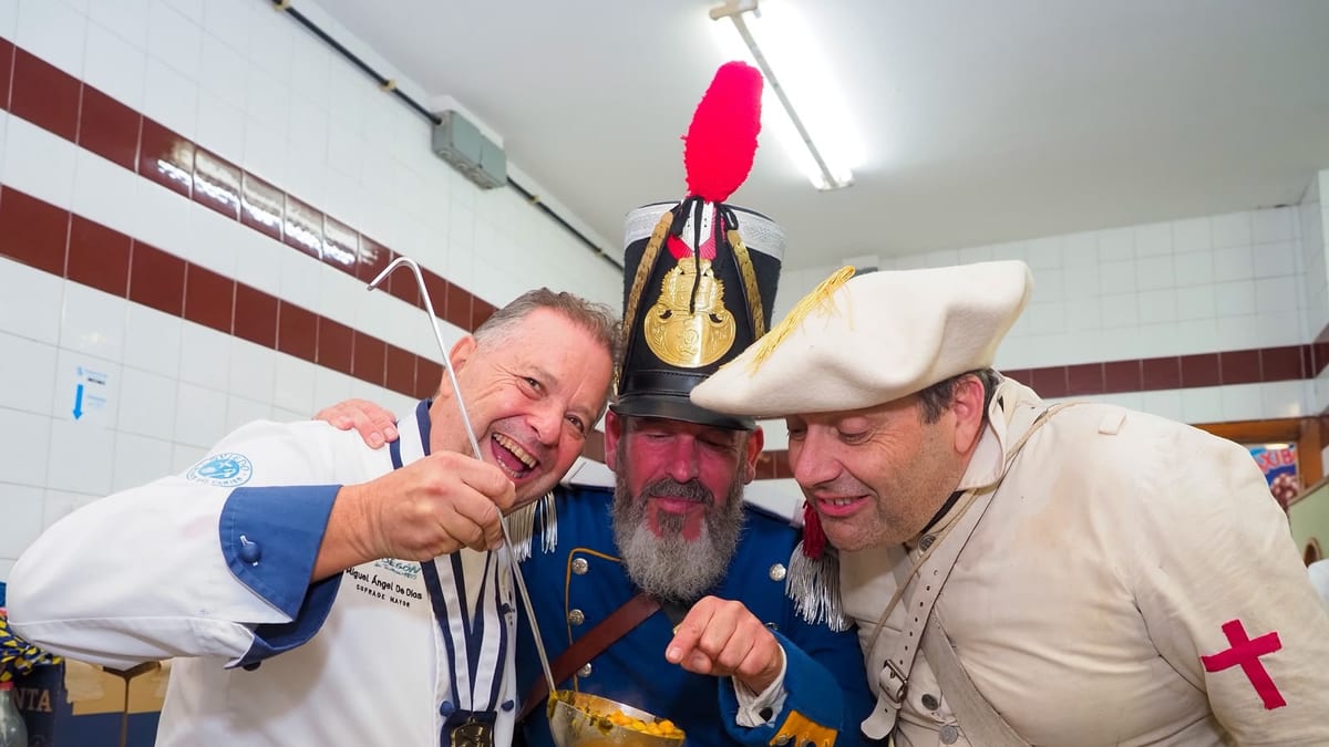 Participantes en la recreación histórica del Desarme de Oviedo alrededor de una olla grande durante el Menú de la Paz, compartiendo comida tradicional asturiana