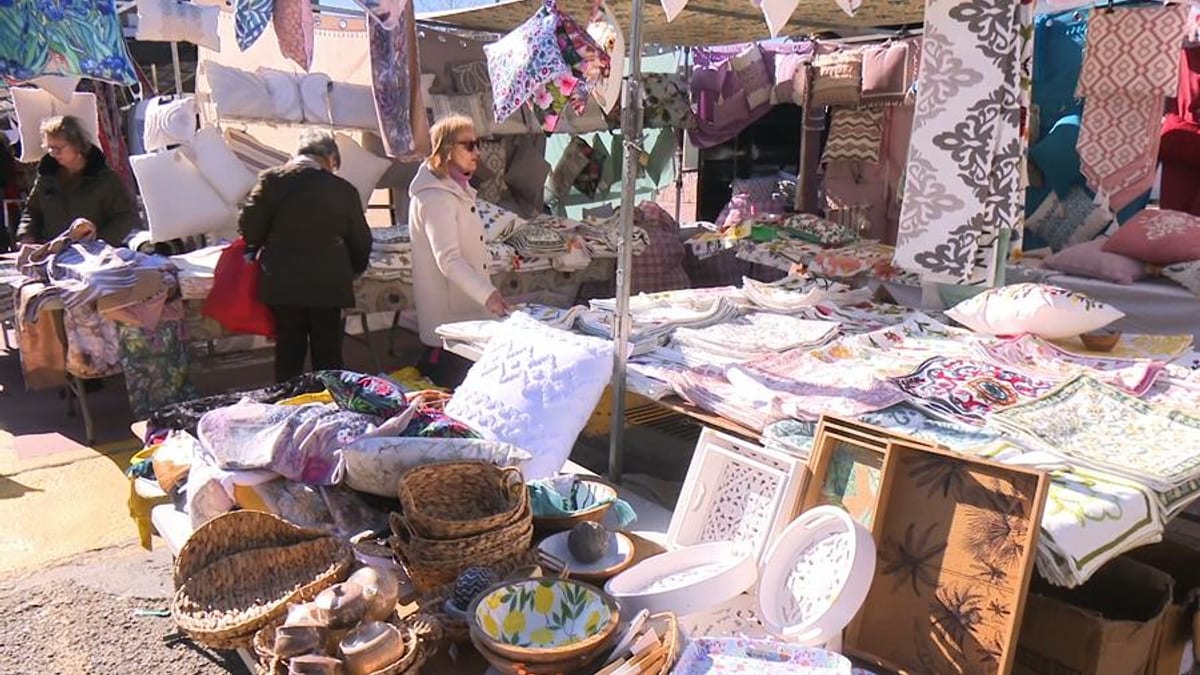 Mercadillo municipal al aire libre con textiles, ropa y artesanías expuestas en San Sebastián de los Reyes