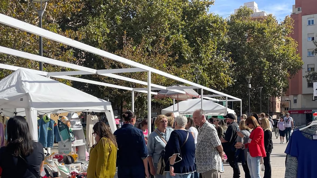 Mercado Outlet de Castellón con múltiples puestos bajo estructuras de tela blanca, visitantes circulando entre comercios y ambiente de compras familiar