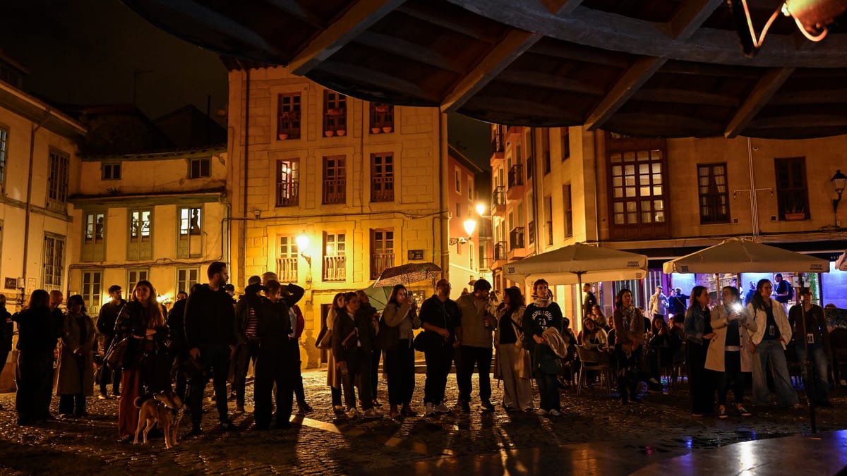 Plaza nocturna de Oviedo durante la Noche Blanca con edificios iluminados, personas reunidas y ambiente festivo
