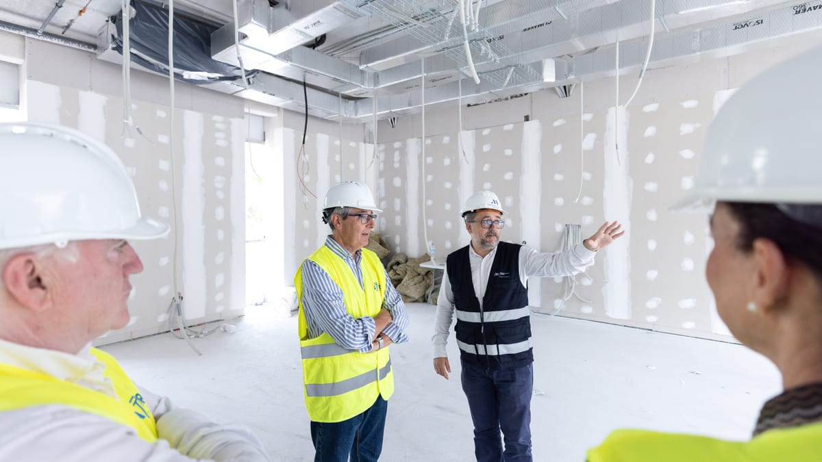 Interior de la construcción del nuevo parque de bomberos de Rincón de la Victoria con trabajadores equipados con cascos y chalecos de seguridad