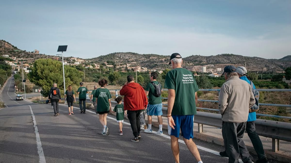 Grupo de participantes en el paseo guiado por las urbanizaciones de montaña de Castellón, recorriendo la carretera con paisaje montañoso de fondo