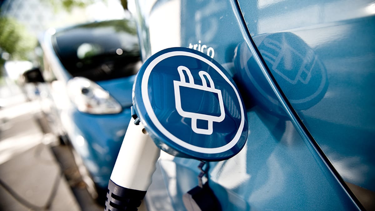 Cable de carga eléctrica conectado a un vehículo eléctrico azul para demostrar la infraestructura de carga del Plan Renove Vehículos Andalucía