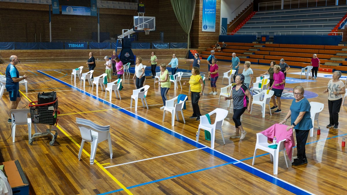Actividad de mantenimiento físico en el Polideportivo Andrés Estrada de Huelva con personas mayores realizando ejercicios adaptados en grupo