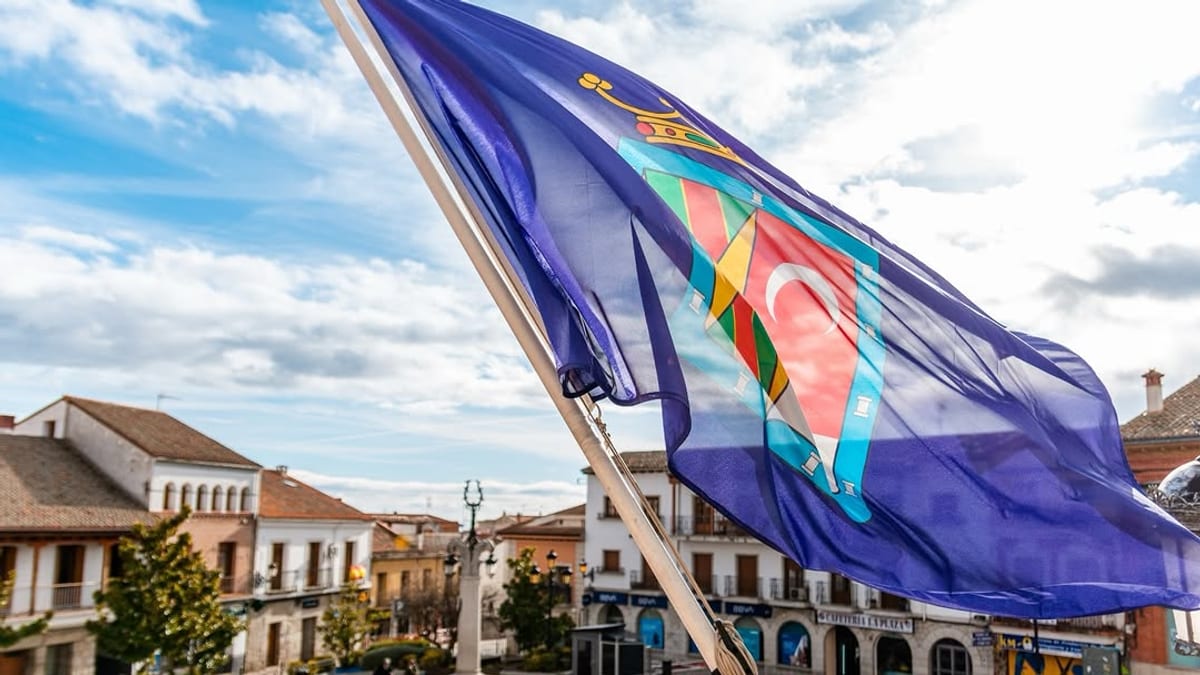 Bandera de Colmenar Viejo ondeando en una plaza municipal durante el anuncio de los presupuestos de 2027