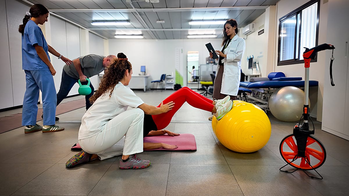Sesión de fisioterapia y rehabilitación con equipos de ejercicio como pelota de estabilidad y bicicleta estática en la Unidad de Esclerosis Múltiple del Virgen Macarena