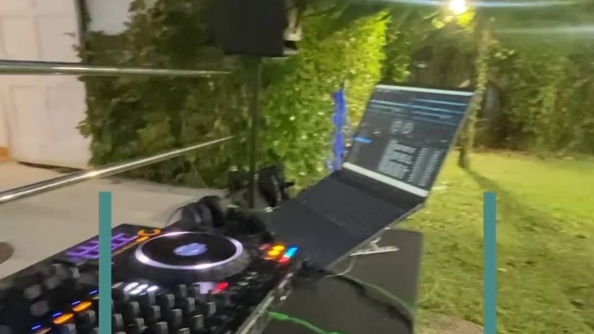 Configuración de DJ con equipo de audio, computadora portátil y luces en el jardín nocturno de la biblioteca Adolfo Suárez durante la Reading Party de Cádiz