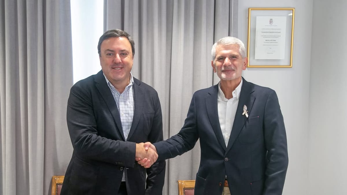 Dos persoas en traxe de negocios estrechando mans nunha reunión de traballo