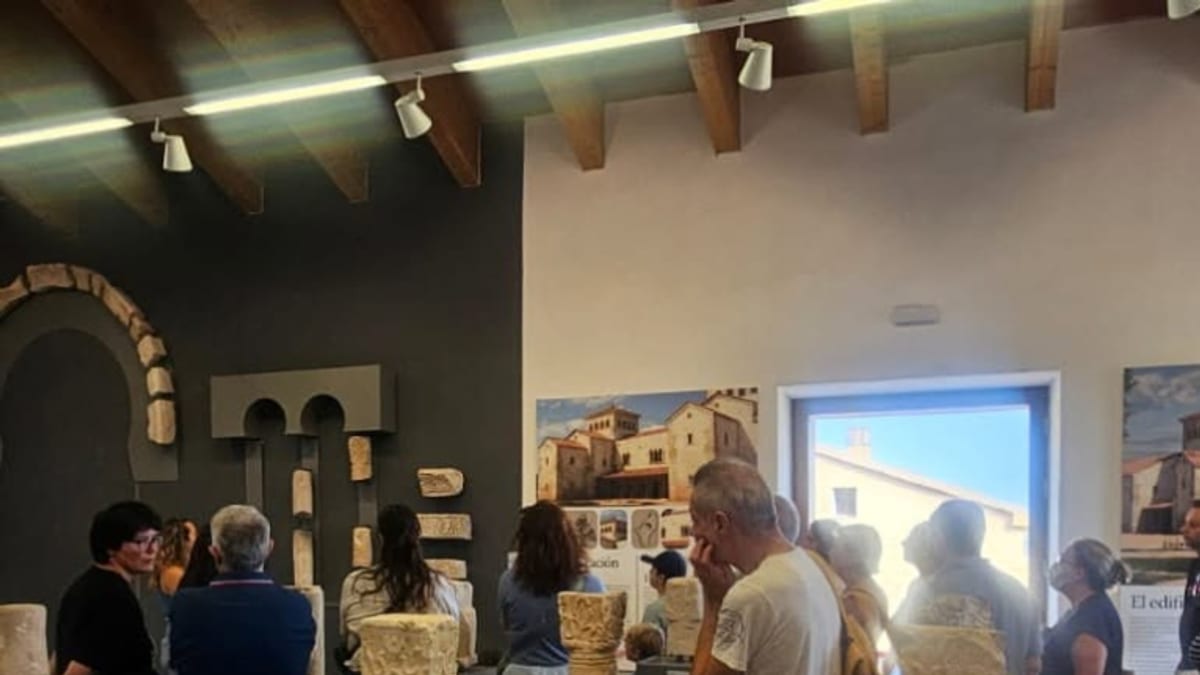 Museo o galería de arte con visitantes observando esculturas y artefactos expuestos