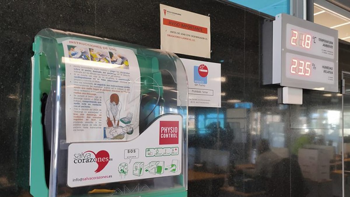 Desfibrilador automático externo (DAE) en pared con instrucciones de uso y paneles informativos sobre técnicas de RCP
