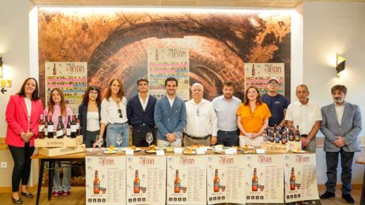 Grupo de personas en evento de degustación con botellas de vino y carteles promocionales de la Ruta de la Tapa