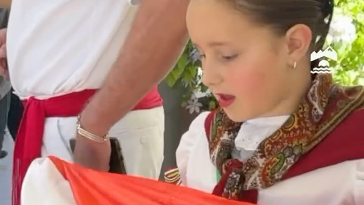 Niña en traje tradicional riojano sosteniendo bandera regional durante celebración de San Mateo en Estadio Español, Chile