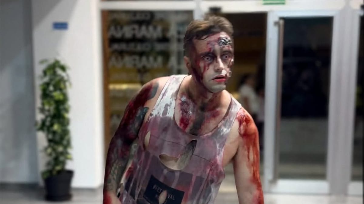 Persona con maquillaje y vestuario de efectos especiales de zombie en escenario urbano del Grao de Castellón durante el Survival Zombie