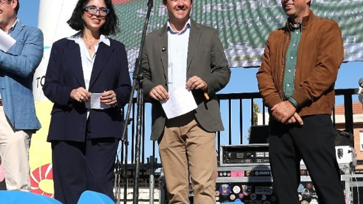 Participantes en el acto de conmemoración del Día de la Parálisis Cerebral en el Fake X-Mas Fest de Toledo, con micrófono y pantalla gráfica de fondo