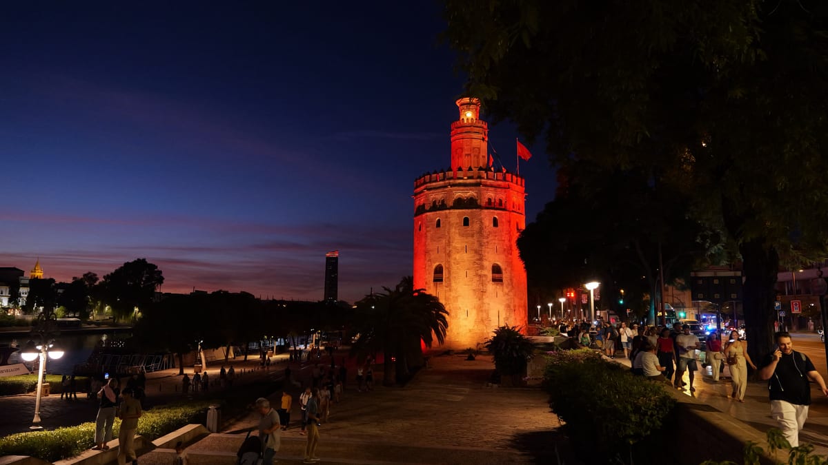 Torre del Oro iluminada con los colores rojo y gualda de la bandera española en el Día de la Hispanidad