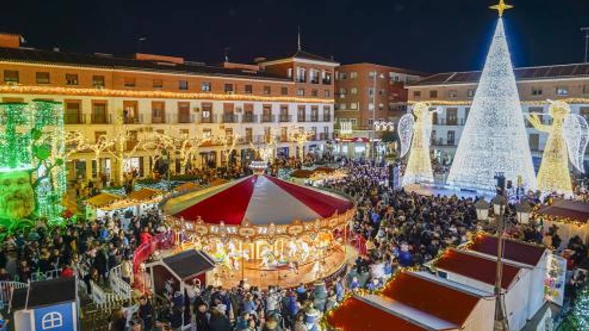 Plaza Mayor de Torrejón de Ardoz decorada con árbol de Navidad iluminado, carrusel tradicional y multitudes de personas durante el Mercado Navideño