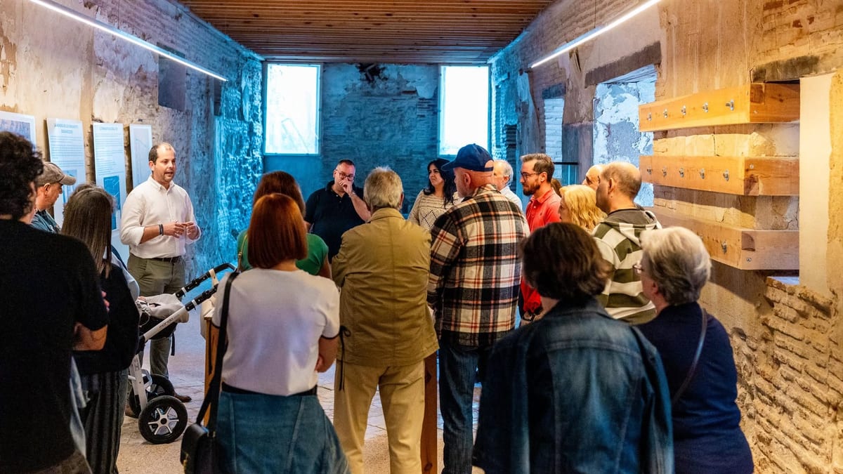 Grupo de visitantes durante una visita guiada a un monumento histórico de Torrijos con muros de piedra