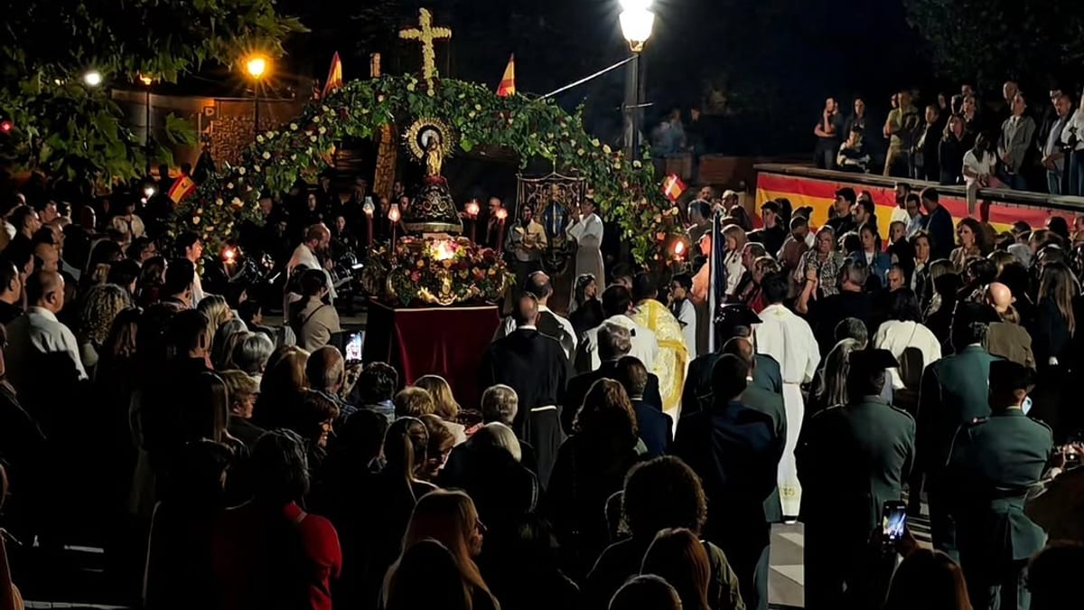 Ceremonia nocturna de procesión de la Virgen del Pilar en Valdemoro con multitud de devotos alrededor de un altar decorado con flores e iluminado