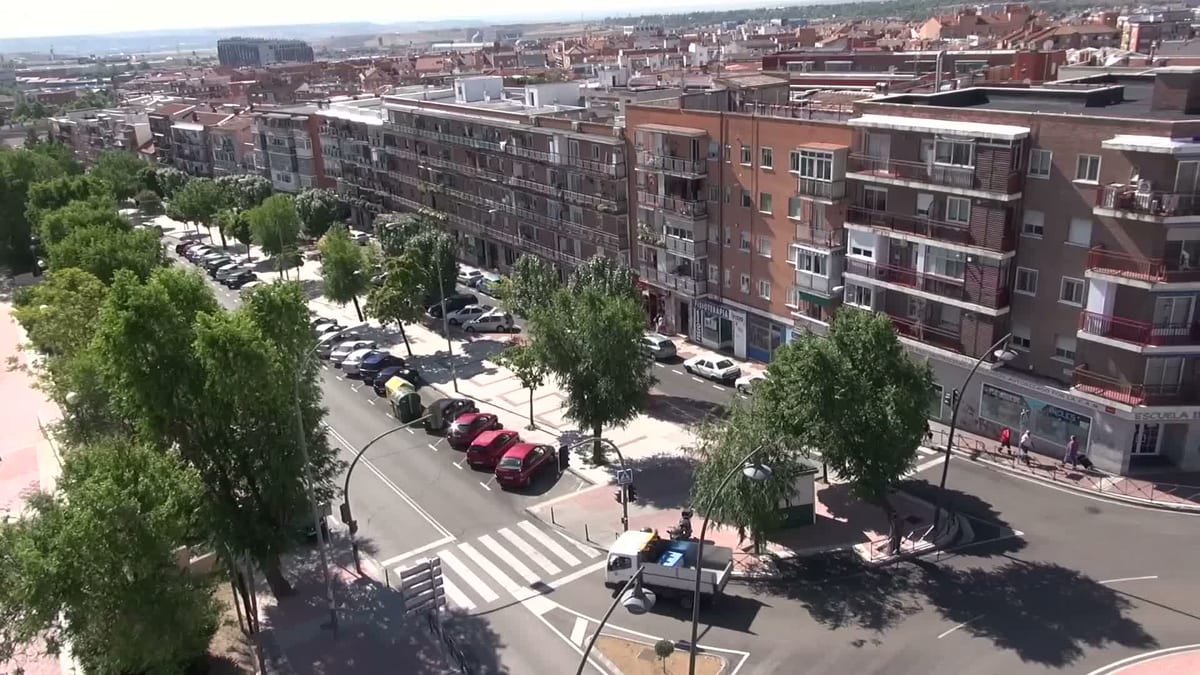 Vista aérea de un barrio urbano con edificios de viviendas, calles, árboles y vehículos estacionados