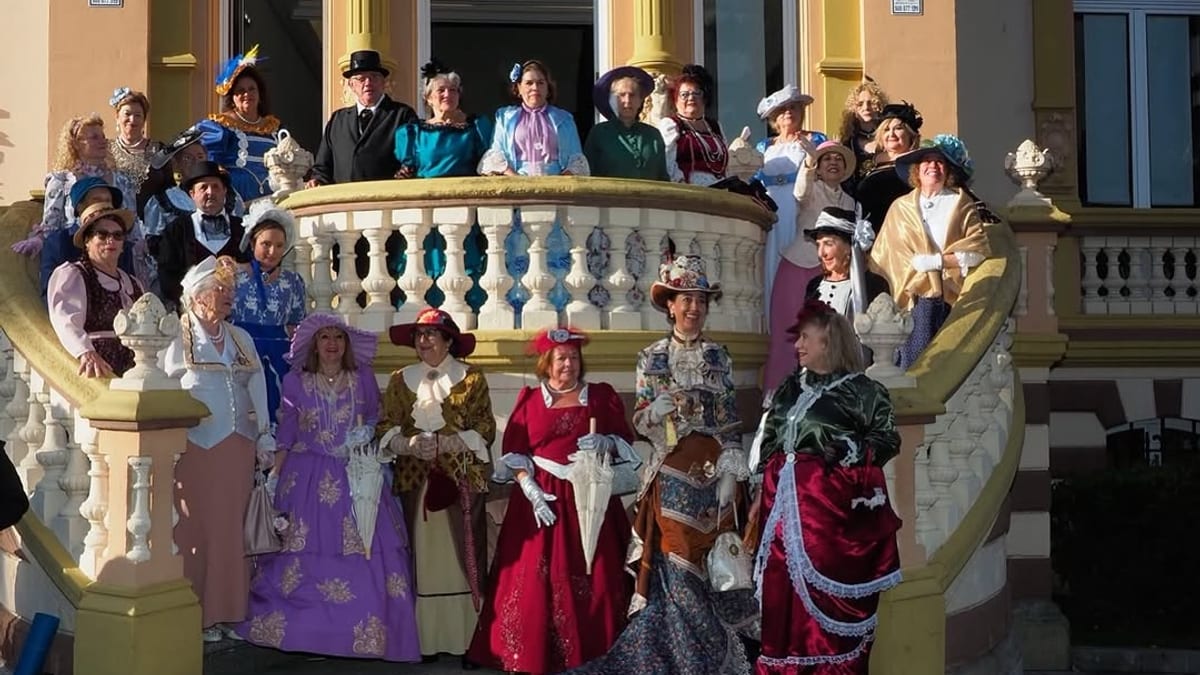 Grupo de personas vestidas con trajes y disfraces históricos del siglo XIX posando en un balcón de Villa Magdalena en Oviedo