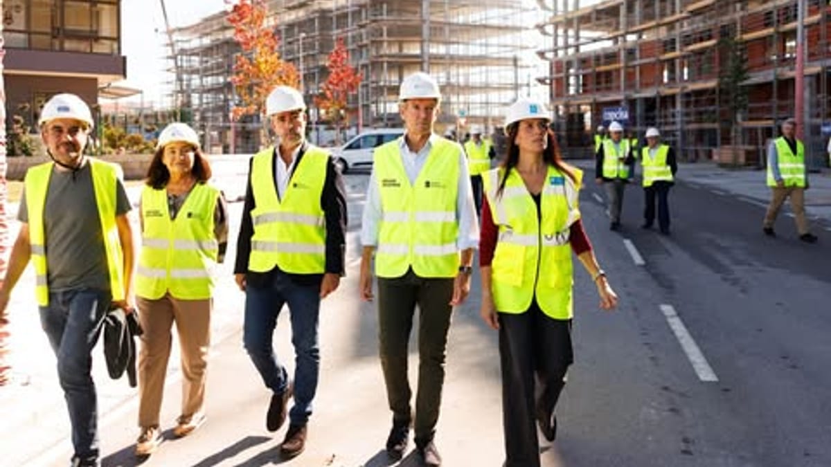 Trabajadores de construcción con cascos y chalecos de seguridad amarillo fluorescente en las obras de viviendas públicas de Navia